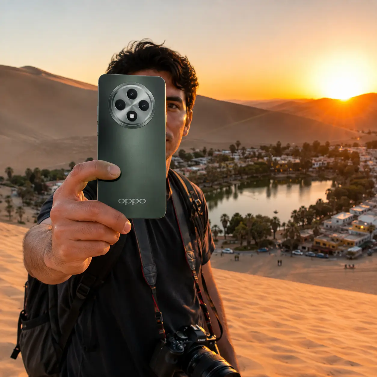 Persona sosteniendo un teléfono Oppo verde en el desierto durante el atardecer frente a un oasis